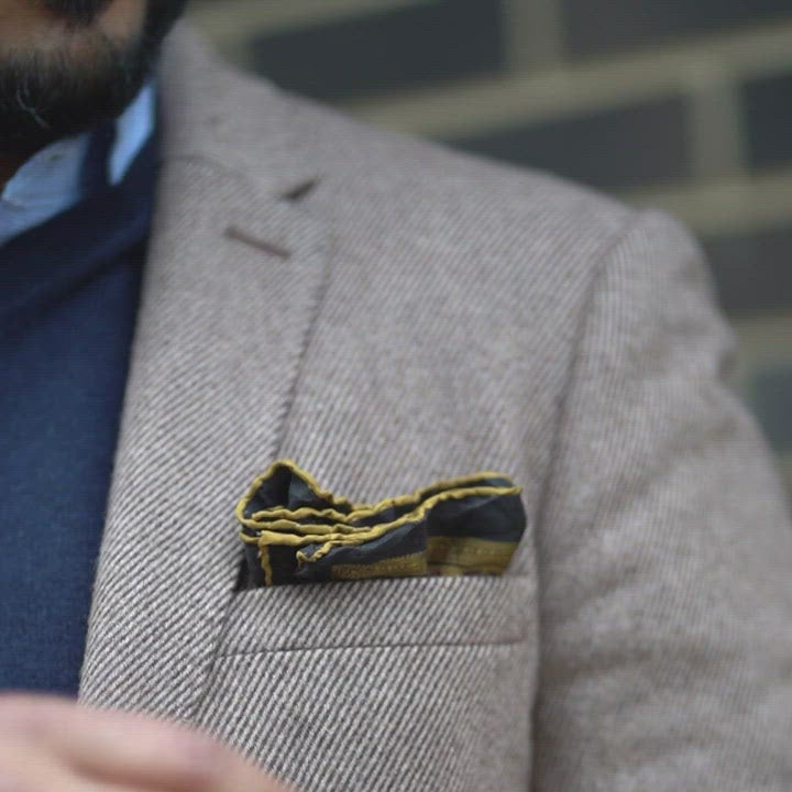 Pocket Square Holder Video of a man in a suit close up shot on the left shoulder pocket and he picks up the pocket square from his jacket pocket to show off the use of the Pocket Square Holder by Best Hombre